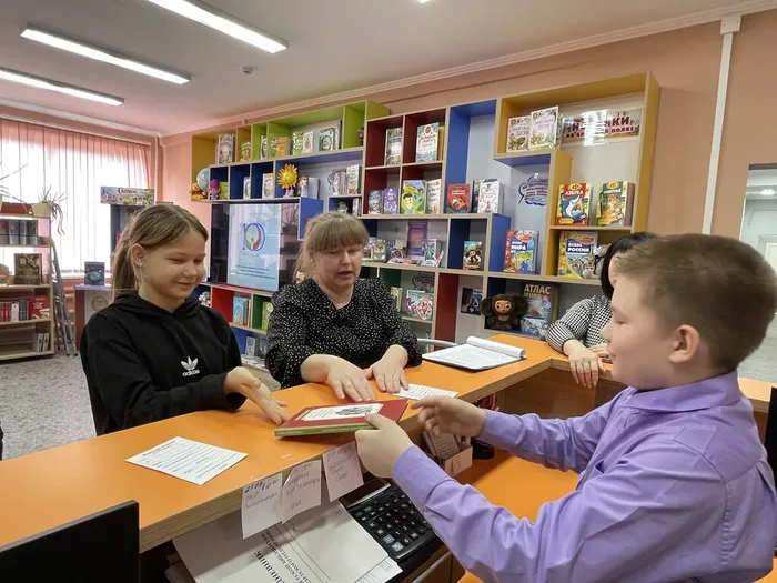 Участник мероприятия пробует себя в роли библиотекаря