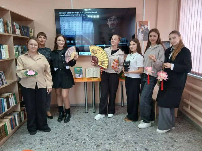 На фото библиотекарь и читатели у книжной выставки Мудрость Китая